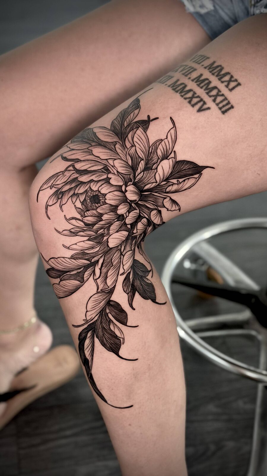 Floral leg tattoo with Roman numeral lettering