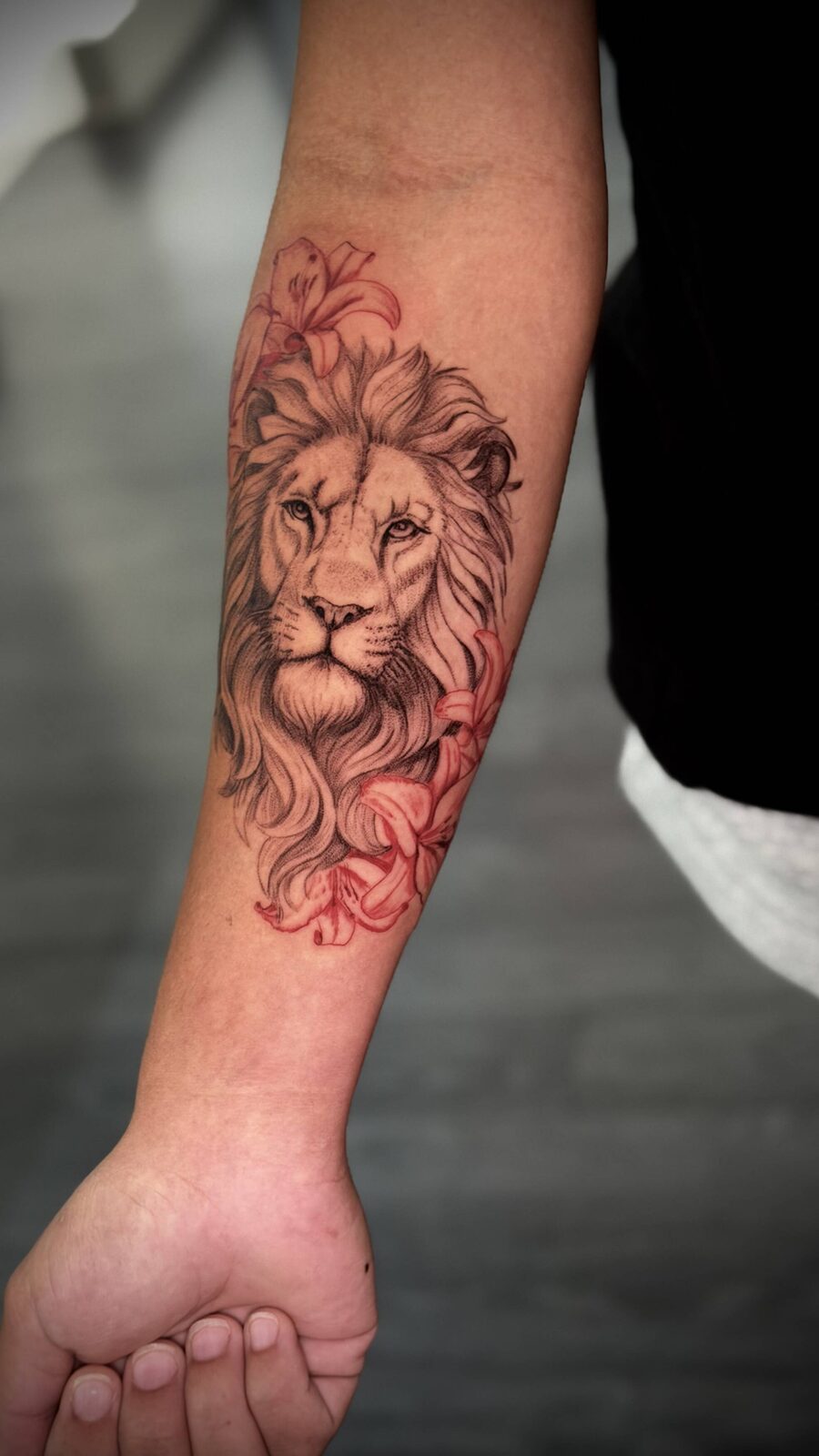 Lion forearm tattoo with red accents