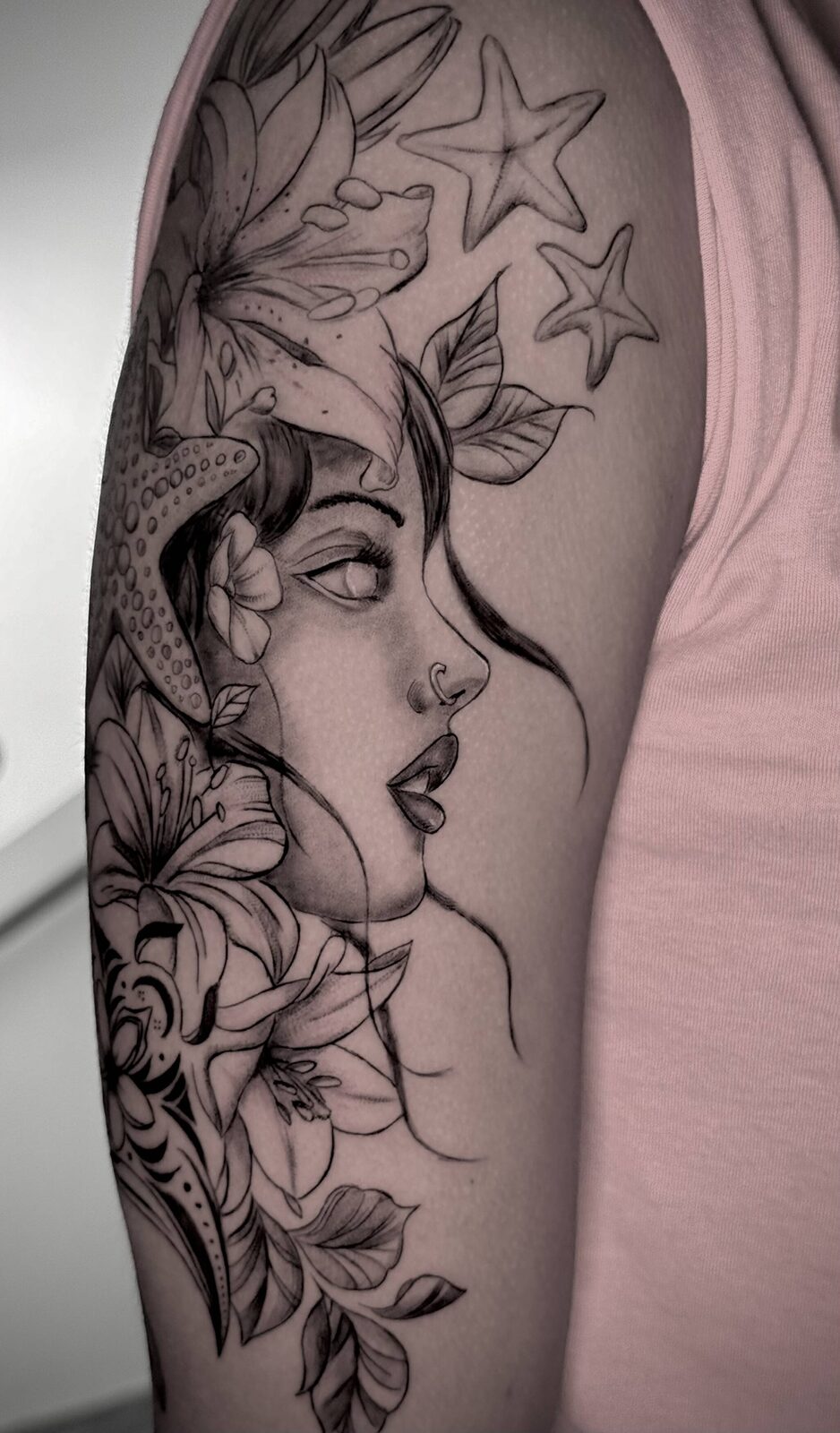 Fine line floral portrait tattoo on an upper arm by Ninonika Tattoos, Orlando