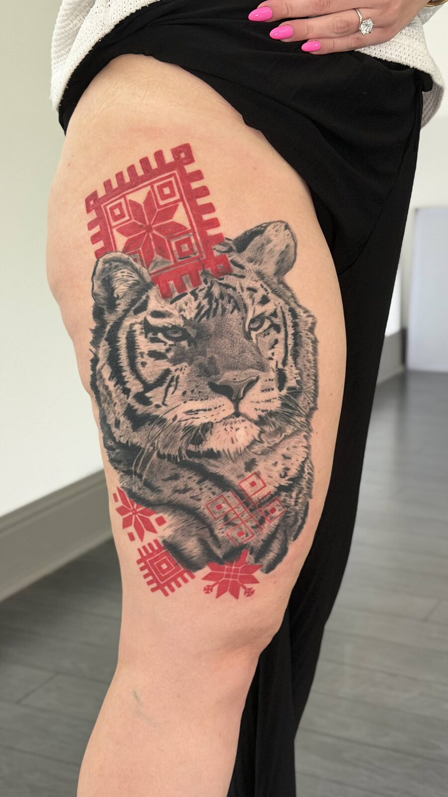 Realism tiger tattoo with red ornamental accents on a thigh